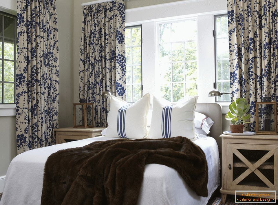 Plavo cvijeće na zavjesama i prugama na jastucima harmonično se kombiniraju u unutrašnjosti spavaće sobe