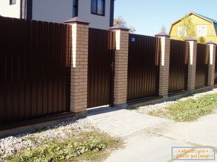 Modularna ograda je tamnosmeđa s ciglom završetkom - klasični žanr, ako govorimo o dizajnu prigradskih područja.