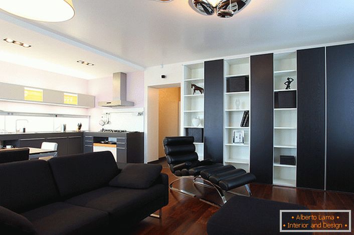 Crna sofa, koja se sastoji od jastuka i male otoman, izrađena je za uređenje interijera u high-tech stilu.