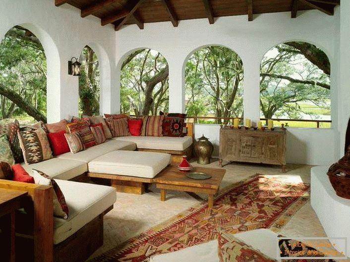Veranda seoskog doma uređena je u skladu s mediteranskim stilom. Zanimljiva značajka je dekor s puno šarenih jastuka.