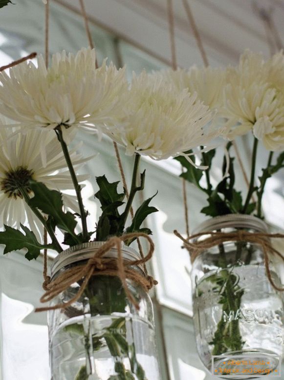 Bijelo cvijeće u konzervama na prozoru