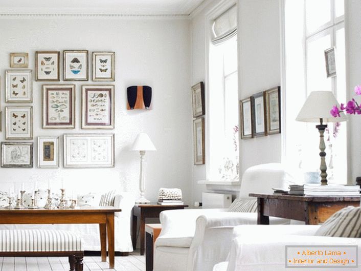 Ugodna dnevna soba u skandinavskom stilu izrađena je u bijeloj boji. Zanimljivo je ukrasiti zid s okvirom različitih veličina.