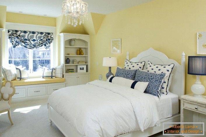 Izbijena žuta boja cilja usklađuje se s bijelim i plavim elementima dekora. Neobična kombinacija je podebljano rješenje za spavaću sobu u seoskom stilu.