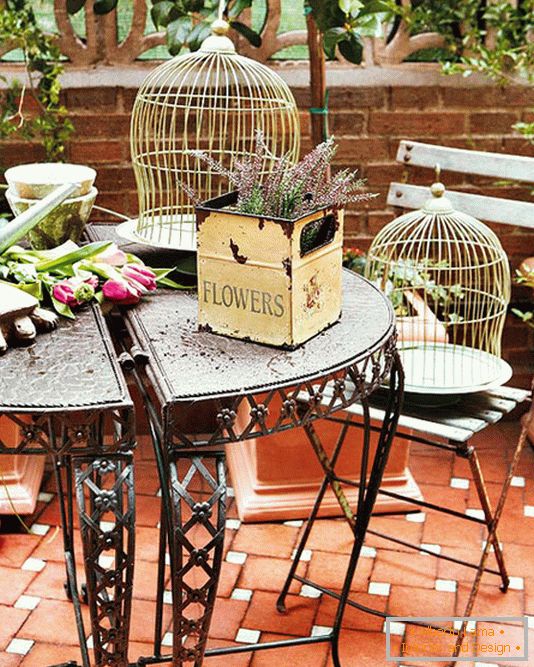 Krivotvoreni stol, kutije s cvijećem i kavezima za ptice