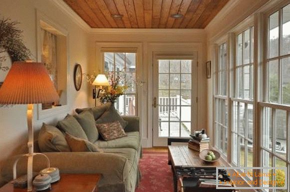 Glazirana veranda s velikim kaučem i svjetiljkama