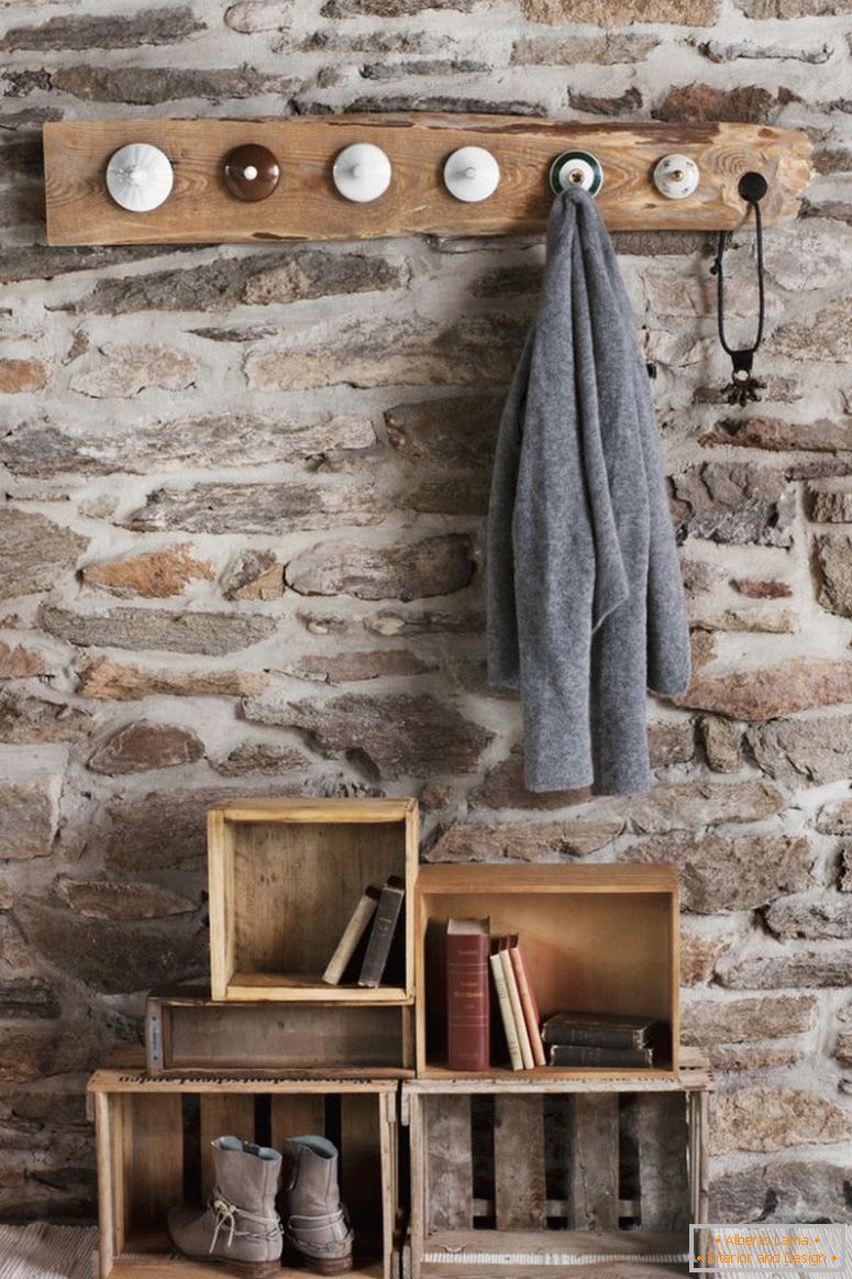 Rustikalni DIY garderoba u sobi sa kamenim zidom; zaštitne klinove od starih porculanskih poklopaca i starih drvenih sanduka na podu kao skladišta