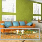 Narančasta kauč s plavim jastucima na pozadini zidova pistacija
