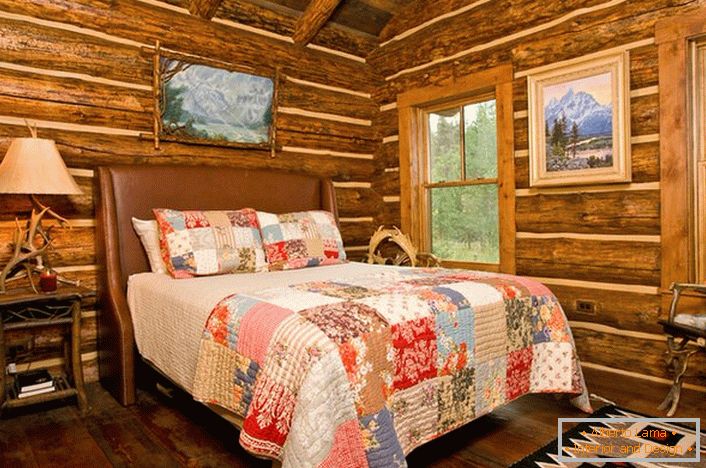 Spavaća soba u rustikalnom stilu u lovačkom domu. Značajno ukrašavanje zidova uz pomoć log housea. 