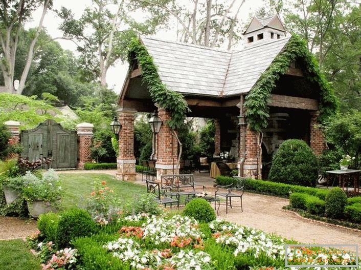 Elegantna jednostavnost otvorenog sjenica u stilu planinske kuće očarava organski u luksuznom, ugodnom vrtu. 
