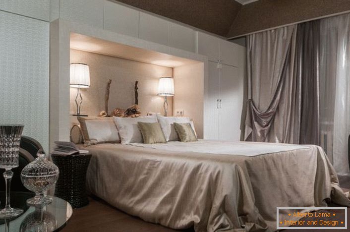 Interijer noble spavaće sobe u stilu art-deco. Pozornost se privlači funkcionalnim ormarima bijele boje. Zahvaljujući njima, soba postaje prilično prostrana i svijetla.