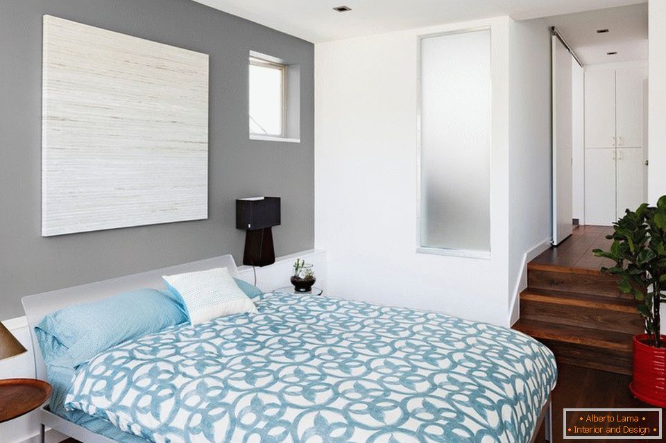 Plave posteljine i sivih zidova u spavaćoj sobi