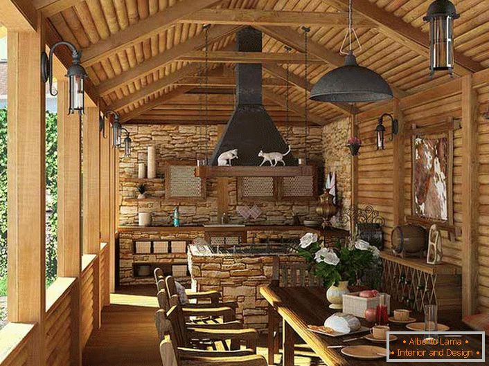 Mala kuhinja s roštiljem na verandi seoske kuće. Stil zemlje se očituje prije svega ukrašavanjem zidova i stropova drvenim okvirom.