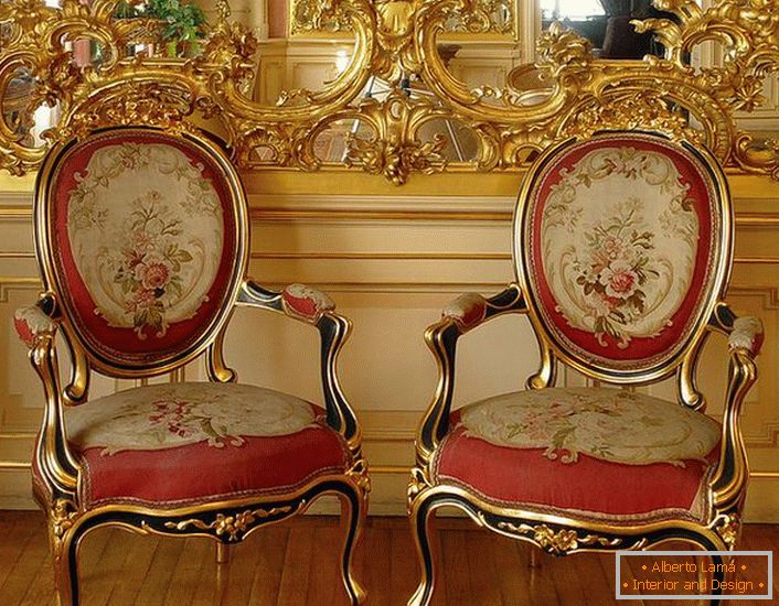 Ogledalo zlatne boje zrcala i stolice s crvenim mekim tapeciranjem - sjajni predstavnici baroknog stila.