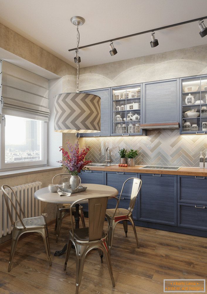 Blijedo plava boja kuhinjskog serija je izvrsno rješenje za eklektičnu kuhinju. Primjer savršeno odabrane rasvjete, koja zasebno osvjetljava radni prostor i stol za blagovanje.
