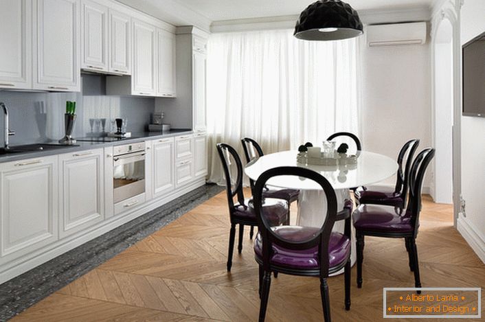 Bijela kuhinja interijera s naglascima tamnosive boje u eklektičnom stilu. Zanimljive stolice s prozirnim leđima i ljubičastim tapeciranjem.